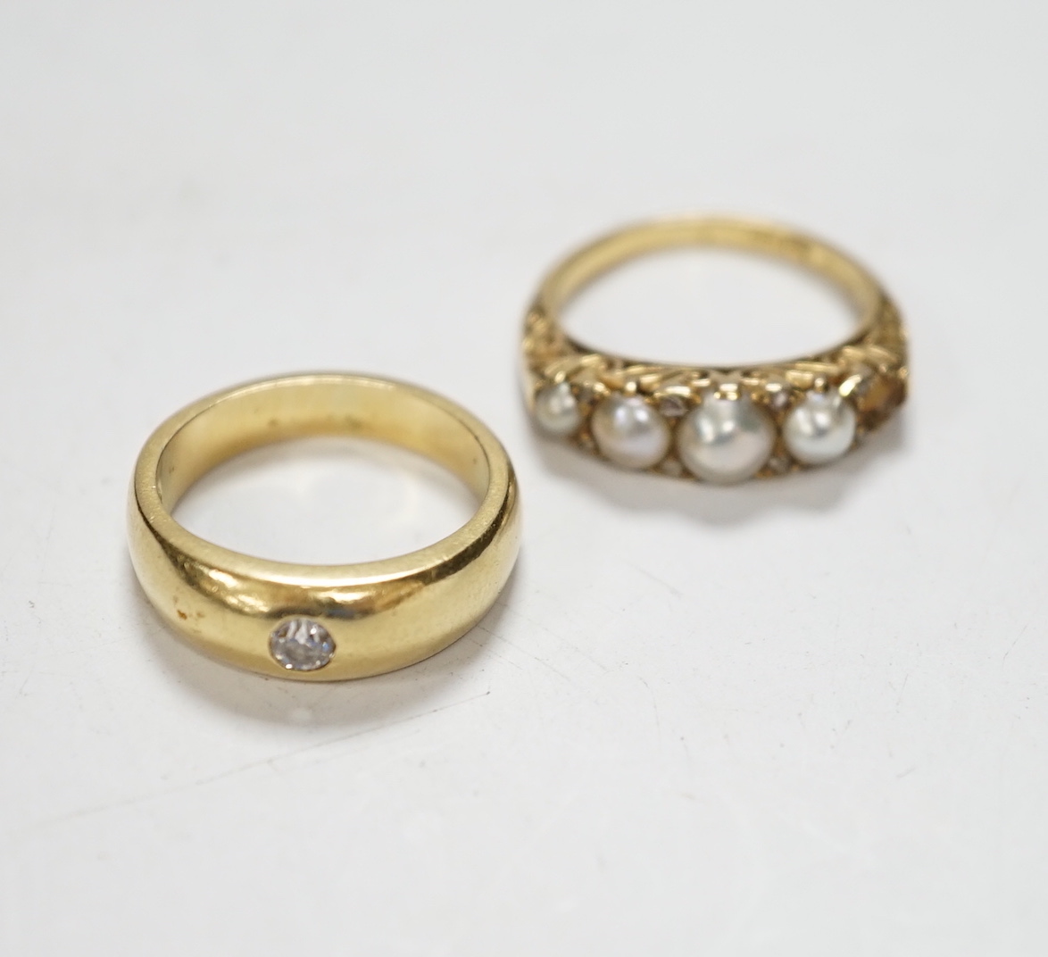 An early 20th century yellow metal and graduated split pearl set half hoop ring, with diamond chip spacers (pearl missing), size K/L, gross weight 4.5 grams, together with a yellow metal and gypsy set solitaire diamond r